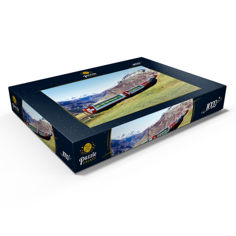 Ein Express mit Panoramafenstern und Blick auf die Wiesen auf den Bergen und schneebedeckten Bergen unter blausonnigem Himmel in Andermatt, Uri, Schweiz 1000 Puzzle Schachtel Ansicht1